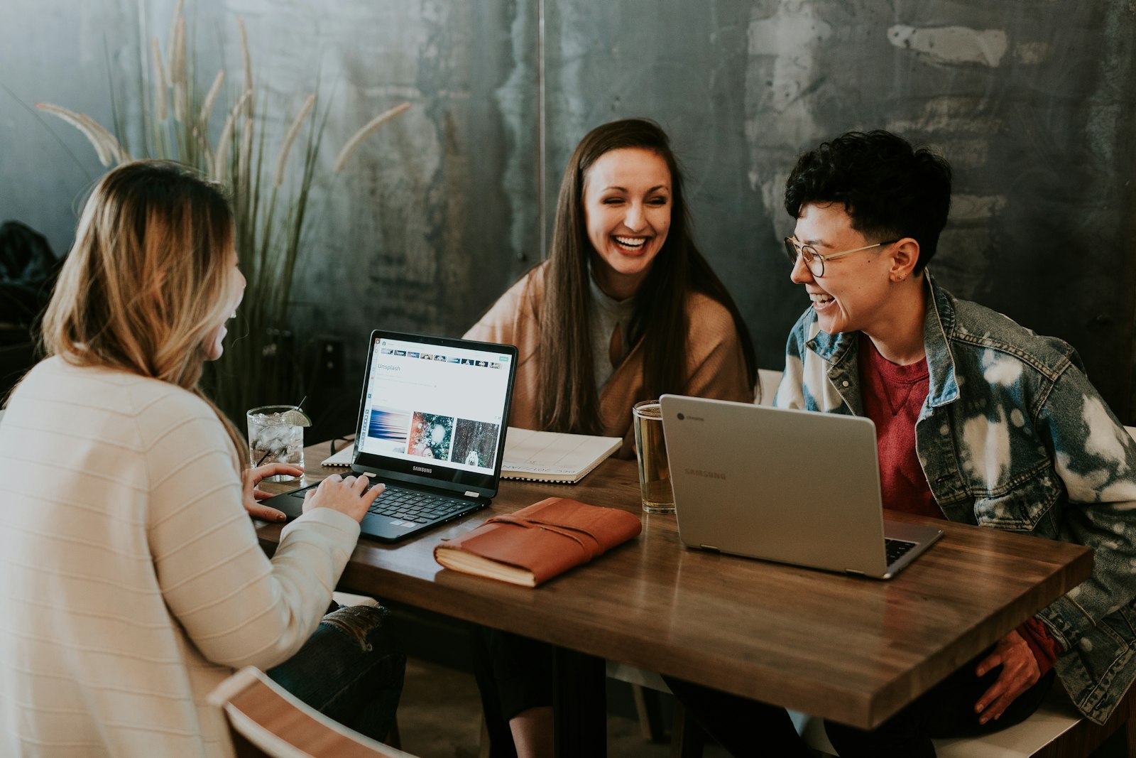 Three people working together at a table with laptops